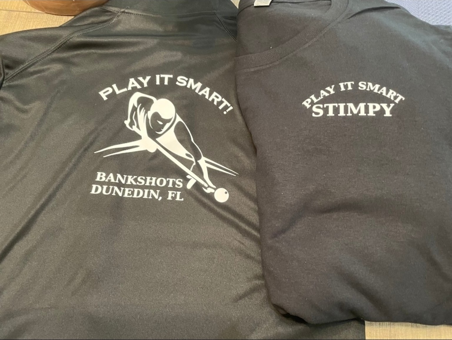 Black printed shirts reading Play It Smart, Bankshots Dunedin, FL with a billiards player graphic