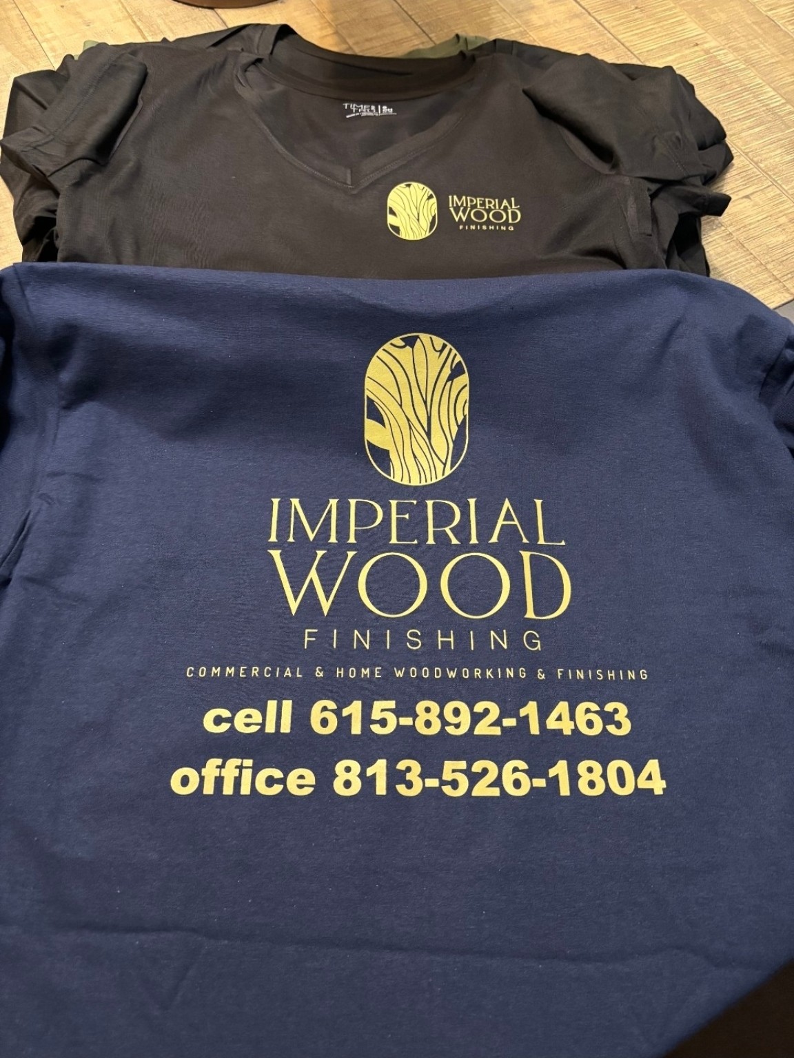Navy and black printed shirts reading Imperial Wood Finishing with wood grain logo and phone numbers