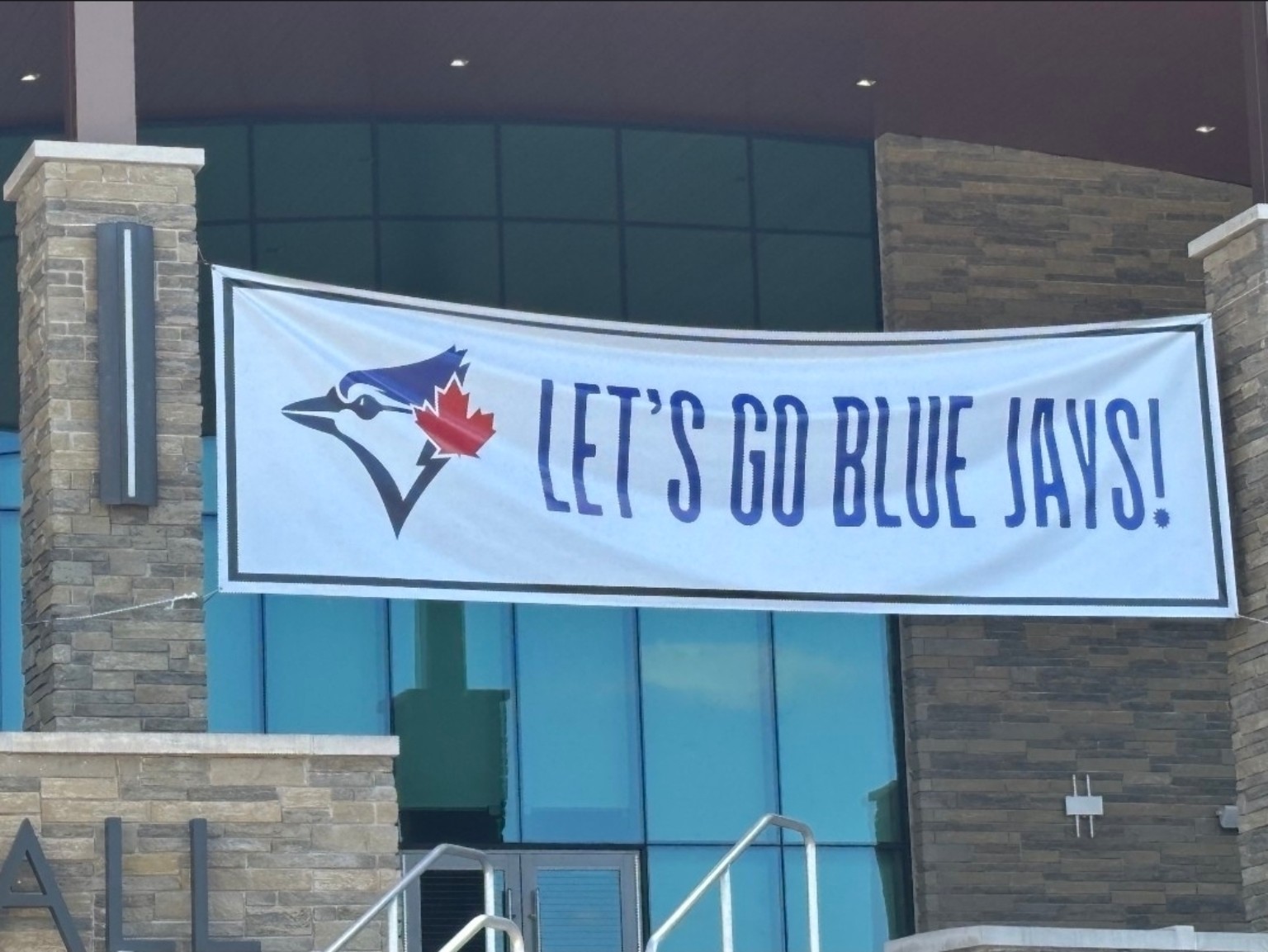 Large printed vinyl banner reading LET'S GO BLUE JAYS! with the Blue Jays logo, mounted on a building exterior